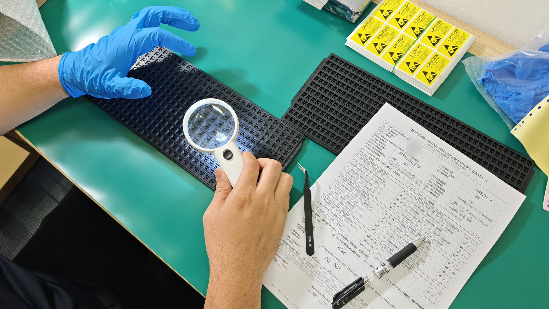 Incoming visual inspection in Shenzhen: components on an ESD tray examined under a magnifier while a written Level 1 inspection report is completed.